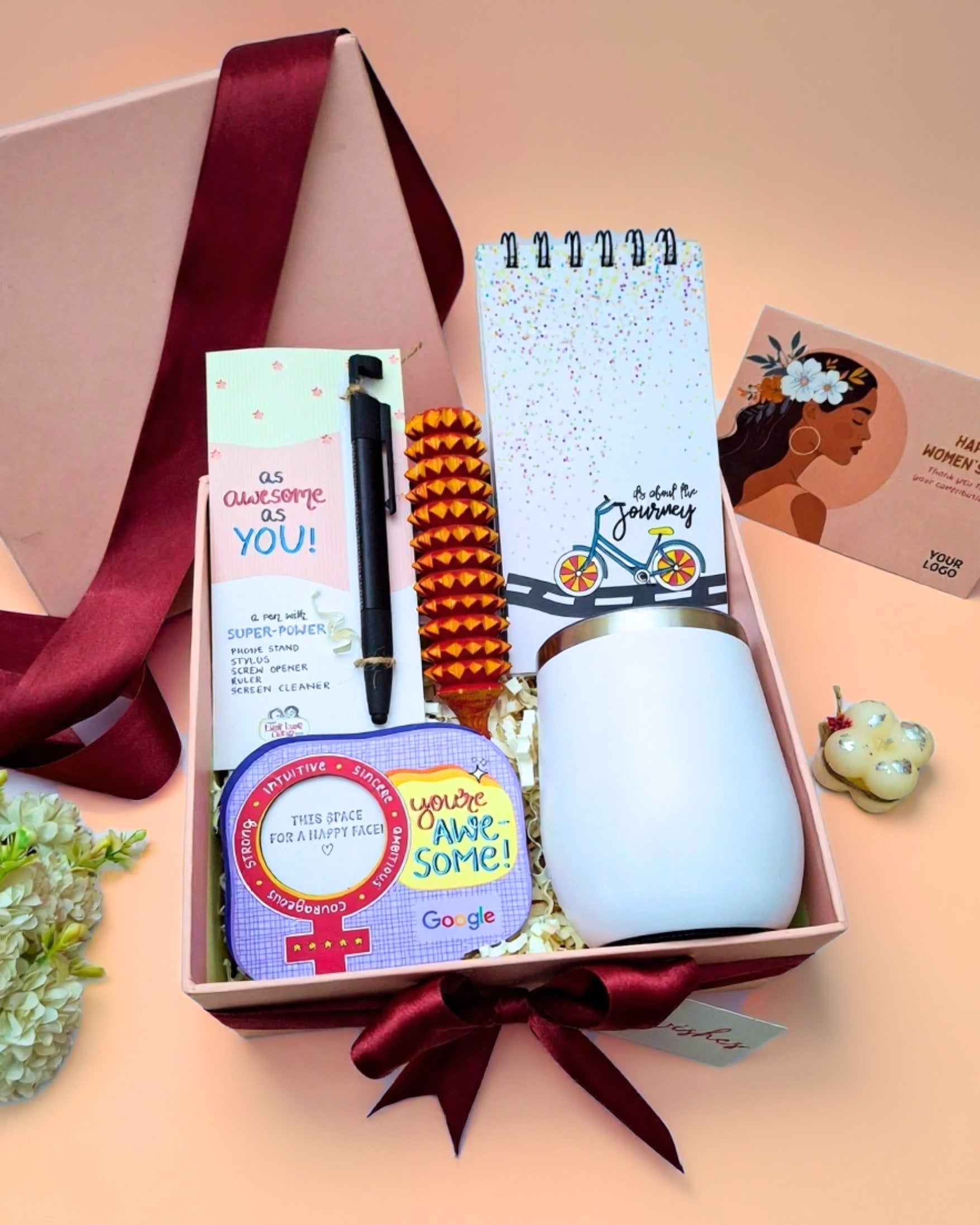 Gift box with a mug, notebook, and other items on a beige background