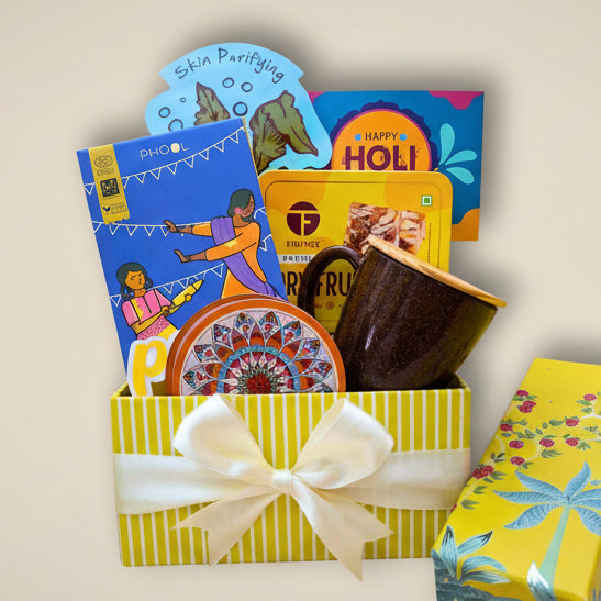 Colorful gift box with a variety of items including edibles and a decorative item on a light background