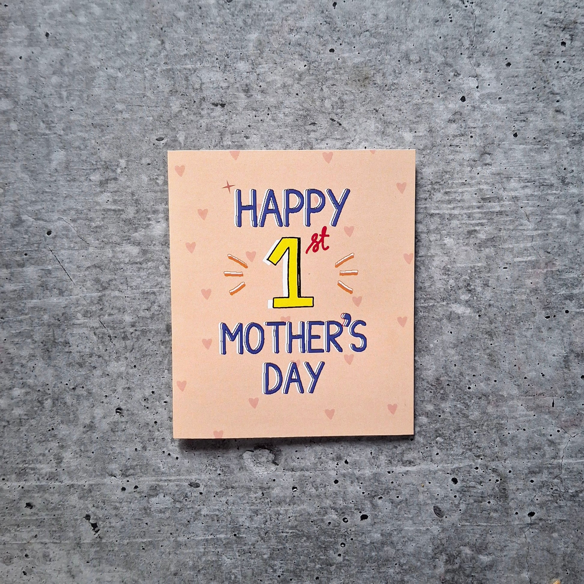 Card with 'Happy 1st Mother's Day' text on a textured gray surface