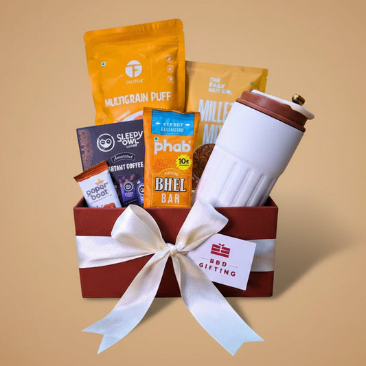 Gift basket with snacks, a coffee mug, and a bar of chocolate on a beige background
