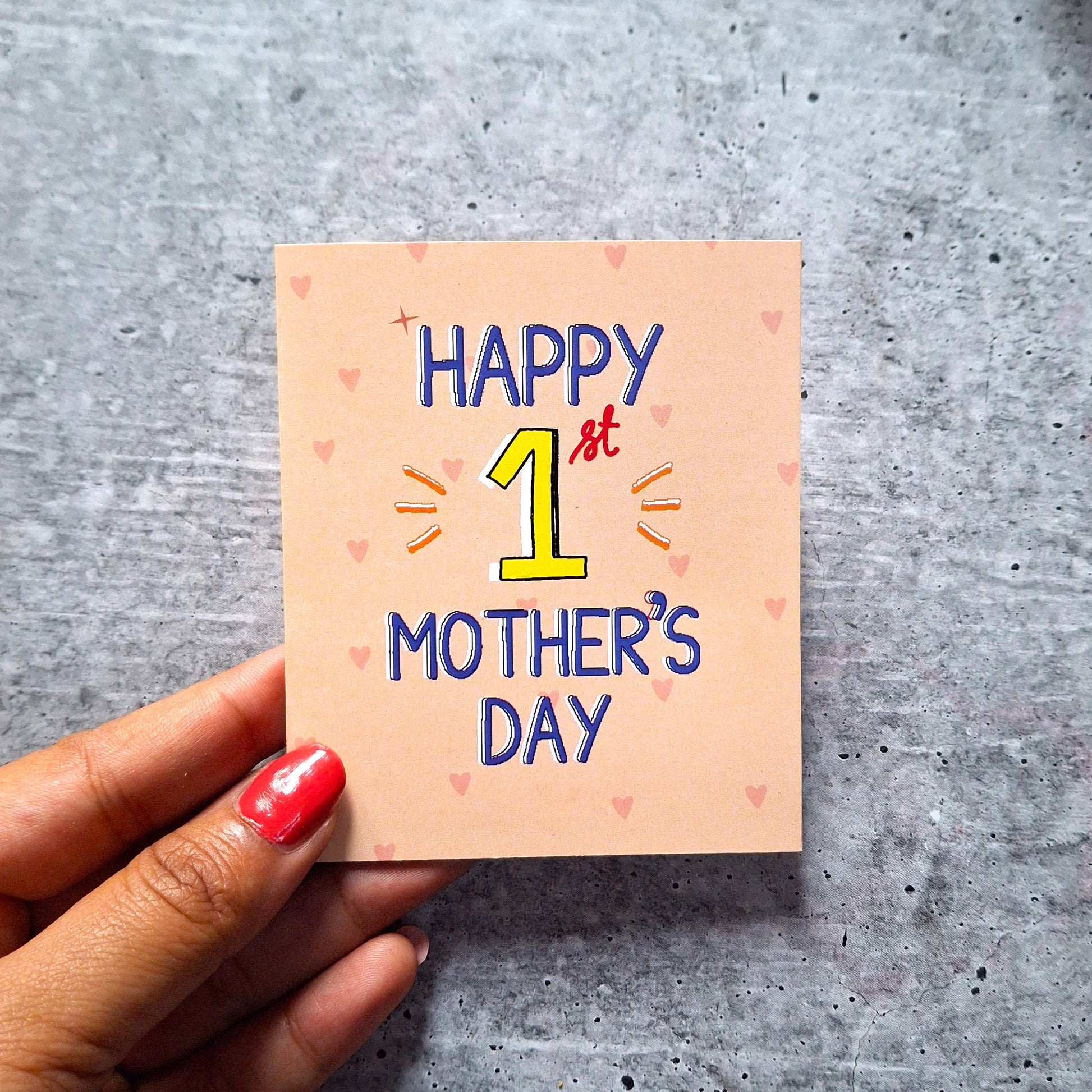 'Happy 1st Mother's Day' card on a gray surface