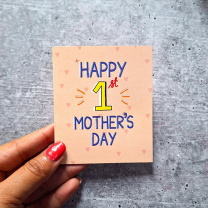 'Happy 1st Mother's Day' card on a gray surface