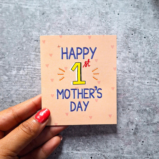 'Happy 1st Mother's Day' card on a gray surface